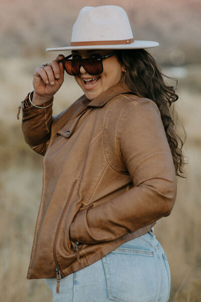 woman wearing leather jacket and hat turning