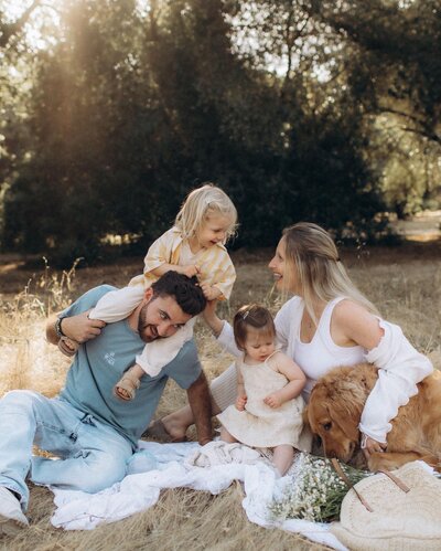 Family with their pet dog and adorable baby spending time in a field.