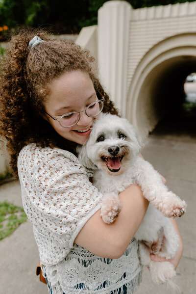 girl smiling holding a small white dog