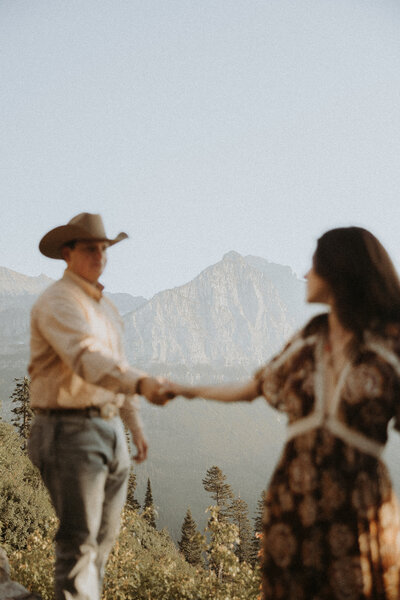 couple holding hands frolicking around an open field in Montana
