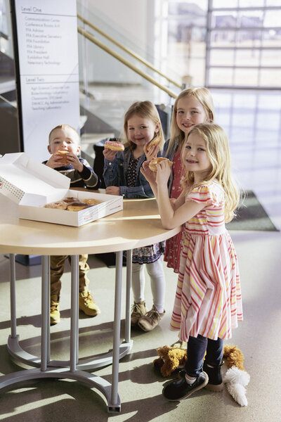 Four kids smiling at the camera with donuts in their hands