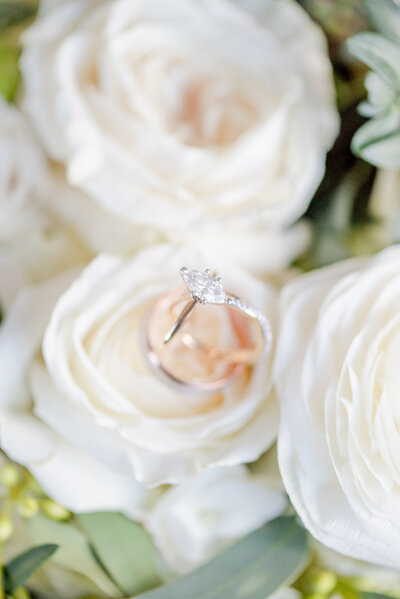 A detail shot of an engagement ring placed in a white rose.