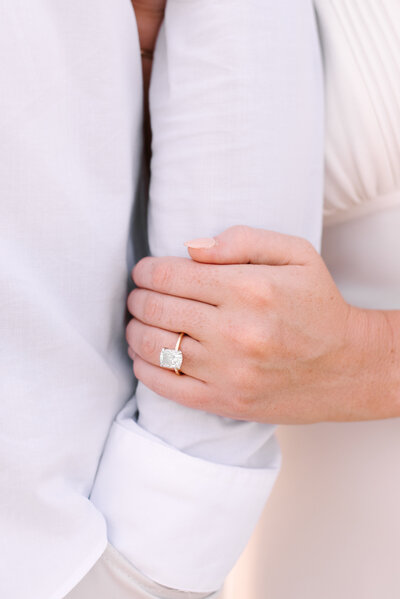 closeup of a couple arm in arm on the engagement ring during a nauset beach engagement session in orleans massachusetts