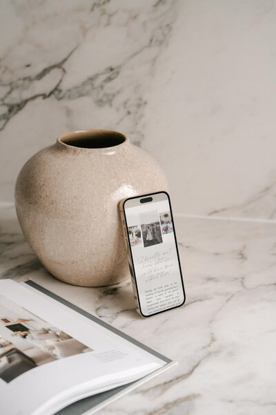 A phone is leaning against an empty vase with a wedding planning concierge website open.