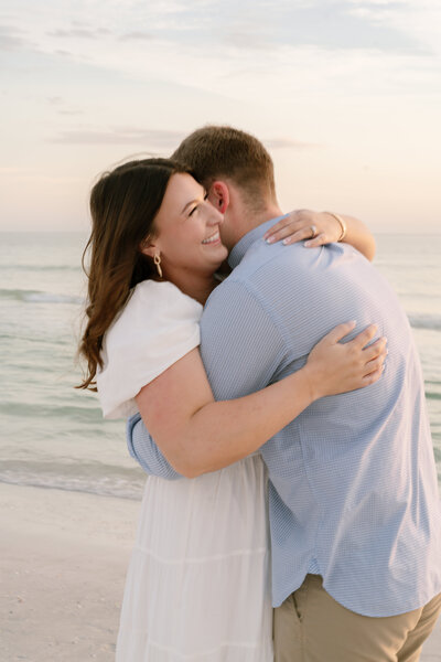 In this picture, the couple is on the beach going for a candid and natural embrace. You can see the woman's face as she smiles and enjoys the moment. 