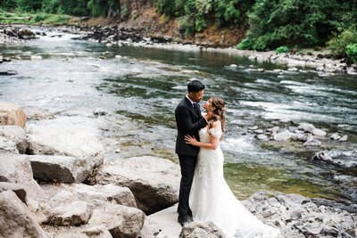 wedding couple poses in washington river under waterfall