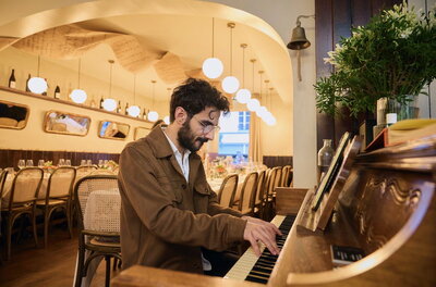 Pianiste jouant en live au Bistro des Poèmes, créant une ambiance poétique et élégante pour les convives