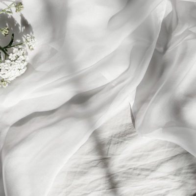 White Fluffy bedding with a stem of white flowers on the upper left hand corner
