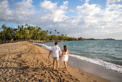 Couple walking hand in hand along ʻAnaehoʻomalu Beach in Waikoloa after a surprise proposal, photographed by Hawaii Adventure Portraits, a Big Island proposal photographer