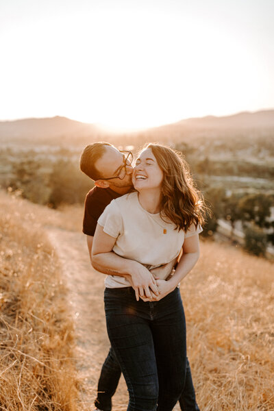 Man kissing a woman on the cheek during their engagement session