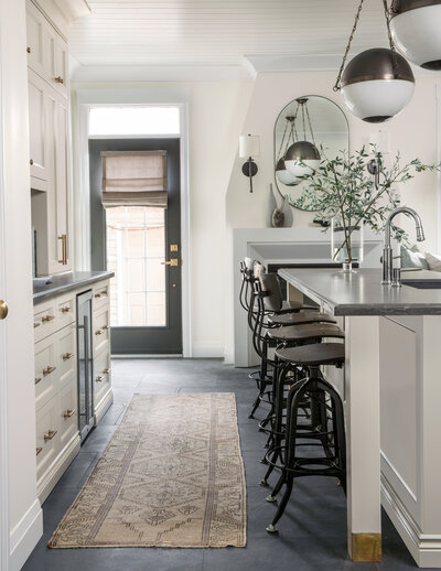 revere pewter taupe beige kitchen cabinets gold hardware slate floors white walls modern art sculptural wall sconces and lighting