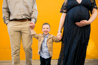 Photo of Parents holding son's hand and Mom holding pregnant belly | Maternity Maine Photographer
