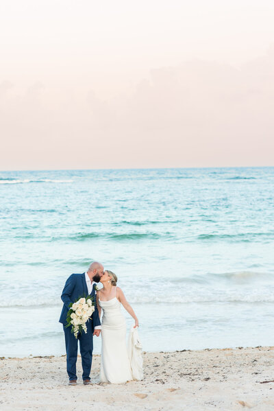 bride and groom kissing by cake