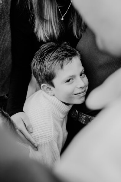 Black and white photo of young boy hugging his family.