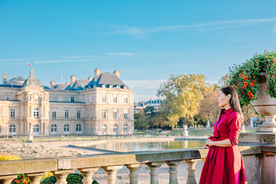 Woman on Solo Photoshoot in the Latin Quarter, Paris standing on bridge wearing red dress