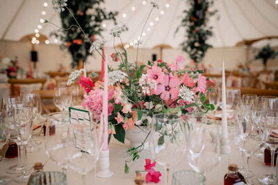 Flowers on the long tables in a white marquee 