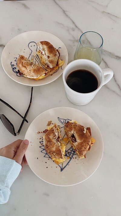 Breakfast sandwiches on plates next to a coffee mug