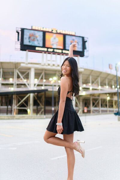 Woman in black dress poses at the top of G10 garage in front of the neyland stadium sign at the university of tennessee knoxville campus