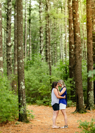 a couple embracing forehead to forehead in a forest