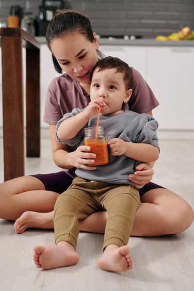 Mother feeding child a glass of juice