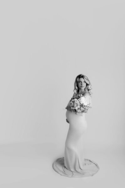 Maternity mama standing in profile holding bouquet of flowers
