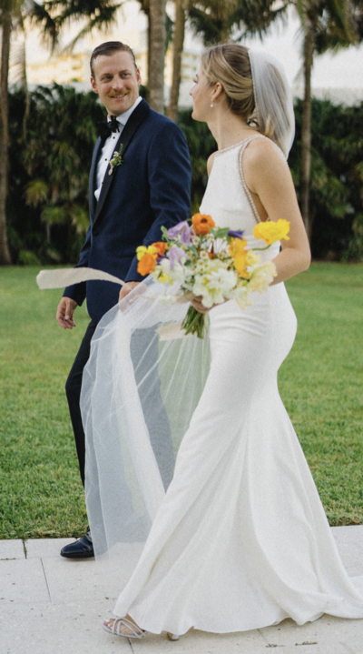 Catherine and Diedrick walking after their ceremony looking at each other accompanied by an incredible Molly in the Sky bouquet.