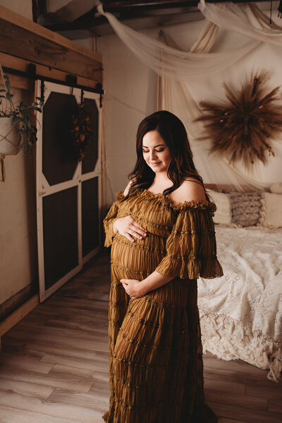 Snuggling her growing baby bump during her maternity session. A momma glows during a intimate Maternity Studio session at the BIsmarck Photography studio of Nikii Pix Photography.