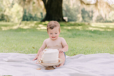 Little boy wearing no shirt Infront of a white cake