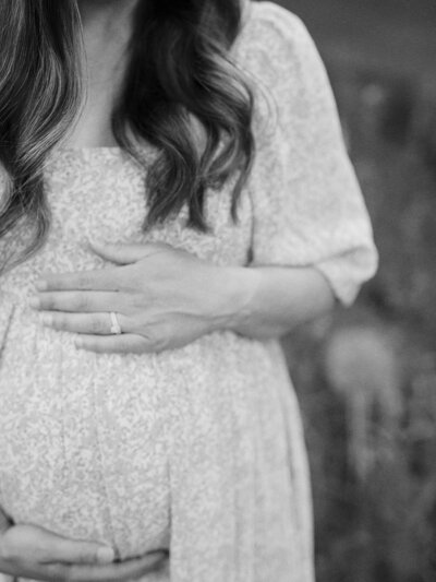 A close-up of a woman holding her pregnancy bump during a maternity photography session in Richmond by Katie Stansfield Photography.
