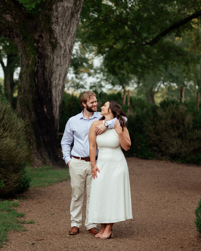 A catholic couple poses in the garden of a historic mansion during their catholic engagement session in thomsons station, tn