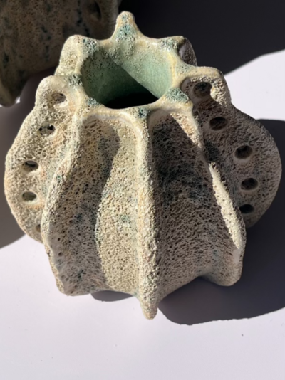 Jill stands beside her teal vase with relief detailing inside of The Studios of Key West