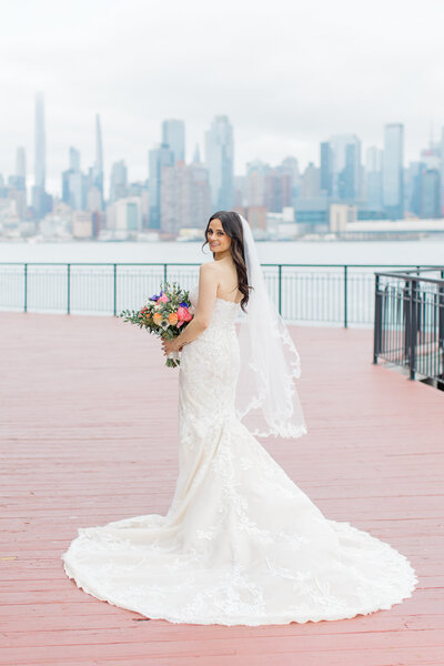 Bride posing for a portrait in a wedding dress with a sheer floral overlay