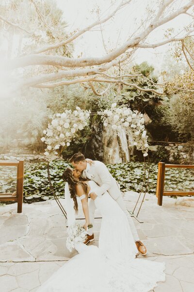 groom dips bride and kisses her for photo