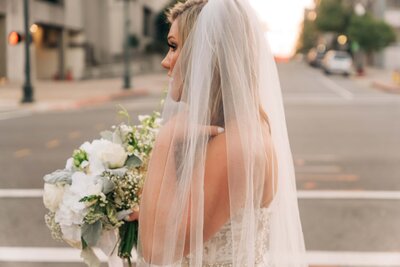A bride with a veil standing on the street, captured by Britt Elizabeth specializing in destination wedding photography.