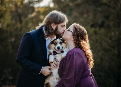 Caitlin Palmertree and Nathan Hancock kiss while their dog smiles at the camera at Lake Arcadia in Edmond, Oklahoma.