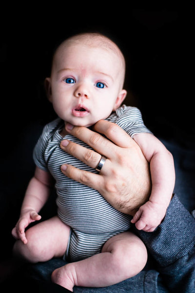 blue eyed baby in dad's hands