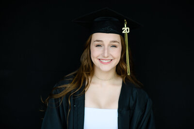 gradutation pictures with high school senior in her cap and gown smiling for a headshot with denver senior photographer