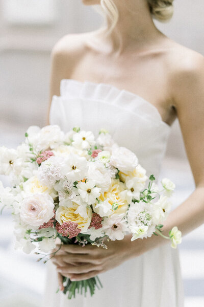 close up of a bride in a wedding dress holding a flower bouquet in city hall