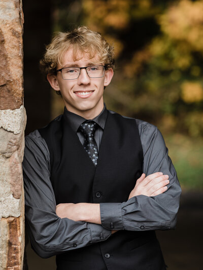 senior boy leaning against brick wall for senior portraits