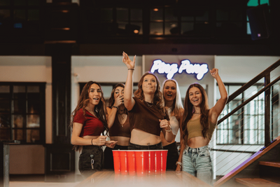 Group of friends cheering and celebrating at a vibrant bowling alley, showcasing an energetic atmosphere perfect for parties and social gatherings.