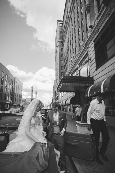 Bride and groom exiting a classic car in front of the Peabody Memphis.