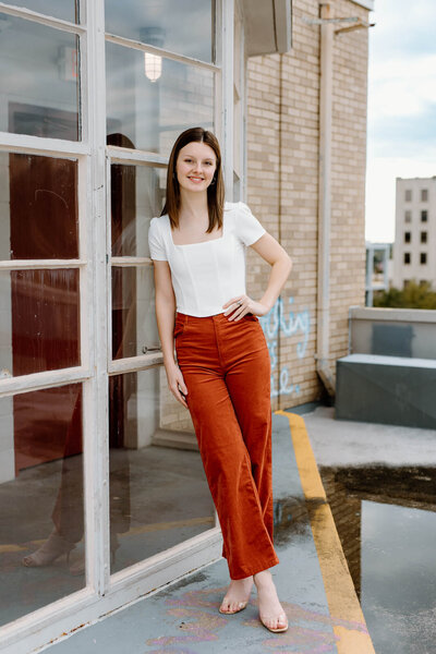 senior portrait of girl on rooftop in white shirt and orange pants