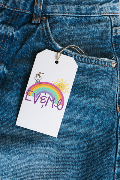 Ev and Me Boutique Logo a cartoon girl looking over a rainbow with a smiling sun displayed on a tag hung from denim