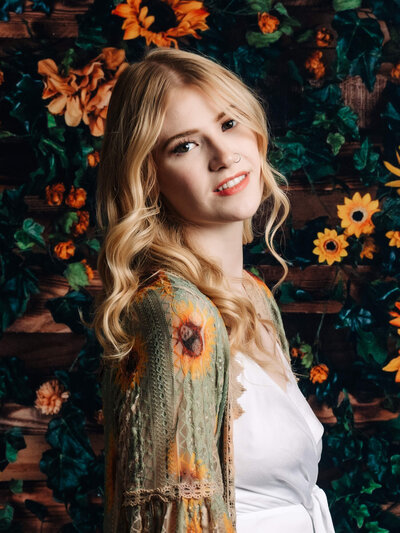 Beautiful girl poses in front of sunflowers in studio in session by Prescott senior photographer Melissa Byrne
