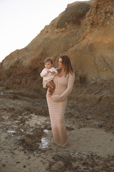 A mother holds her toddler during a calm family photo session at Goff Cove in Laguna Beach, captured by Orange County family photographer Maria Alcantara.