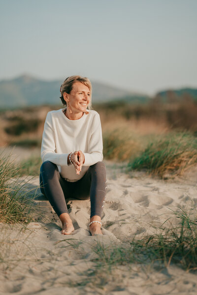 Sylke lächelnd am Strand sitzend