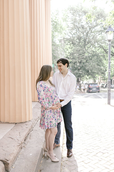 Man and woman looking at each other while they hold her pregnant belly in Alexandria Virginia