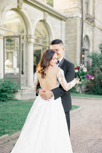 Bride and groom, belly button to belly. button while bride is looking over her shoulder. behind the Eolia Mansion in Harkness park.