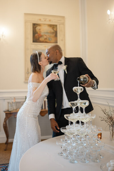 Timeless keepsake of the bride and groom pouring champagne into the glass tower during an elegant, refined, and luxurious wedding in Montreal.