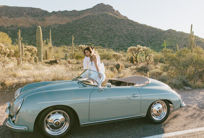 Couple in a classic vintage car during their engagement photo session in Scottsdale, Arizona, with desert views in the background.